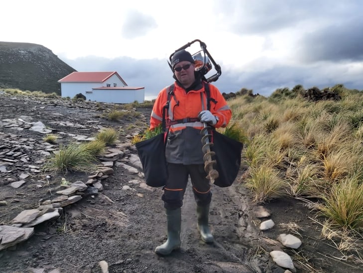 Helfer auf Hummock mit Setzlings-Rucksack und Schneckenbohrer.